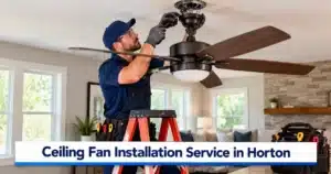 Professional electrician performing ceiling fan installation service in Horton, MI, securely mounting a modern ceiling fan in a residential living room.